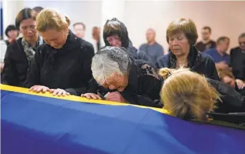  ?? NATACHA PISARENKO AP ?? From right, the wife, the mother and the sister of Army Col. Oleksander Makhachek mourn over his coffin during a funeral service in Zhytomyr, Ukraine, on Friday. Makhachek was killed fighting Russian forces.