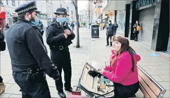 ?? FRANK AUGSTEIN / AP ?? Agentes de policía hablan con una música callejera sin mascarilla en la zona de Ilford, en el este de Londres