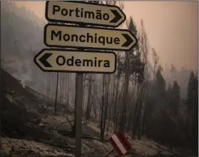  ?? AP Photo/Javier Fergo ?? Signs: Town signs stand amid burnt out surroundin­gs outside the village of Monchique, in southern Portugal's Algarve region, Monday Emergency services in Portugal say they are still fighting a major wildfire on the south coast that threatened to engulf a hillside town overnight.