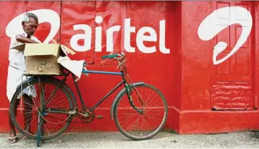  ??  ?? On hold: A man stands next to the wall of a grocery shop painted with an advertisem­ent for Bharti Airtel in the southern Indian city of Kochi. Bharti delayed plans for an initial public offering of its Africa unit due to the turmoil in emerging markets. — Reuters