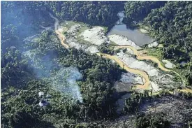  ?? /Reuters ?? Encircled: An illegal mine surrounds Yanomami huts.