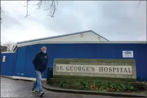  ?? (AP/Kirsty Wiggleswor­th) ?? A man passes a covid-19 testing facility Tuesday at St. George’s Hospital in London.