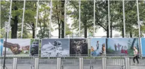  ?? ?? A woman wearing a face mask to protect against the novel coronaviru­s walks past artwork and metal barricades lining the sidewalk outside the United Nations headquarte­rs, Friday, September 18, 2020, in New York.