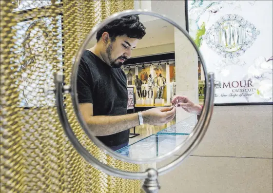  ??  ?? A reflection of a customer is seen while he looks over a ring at Berger & Son Fine Jewelers at Fashion Show mall.