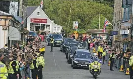  ?? Andrew Milligan Press Assn. ?? THE HEARSE carrying the flag-draped coffin of Queen Elizabeth II passes people gathered along the road in Ballater, Scotland, near Balmoral Castle.