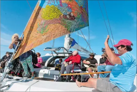  ?? SARAH GORDON/THE DAY ?? Patti Willis, left, of Stonington, and Capt. Will Rey, right, take photos of each other as the ship’s painted sail flies on Friday during a trip with the Impossible Dream. The nonprofit works with Shake A Leg Miami to provide adaptive sailing...