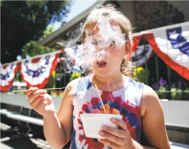  ?? Brittany Hosea-Small / Special to The Chronicle ?? Adalyn Hofmann, 8, eats a bowl of Nitro Puffs from the Nitro Shack at the Alameda County Fair on Thursday. Nitrogen-infused cereal balls are a new cold treat at the fair this year.