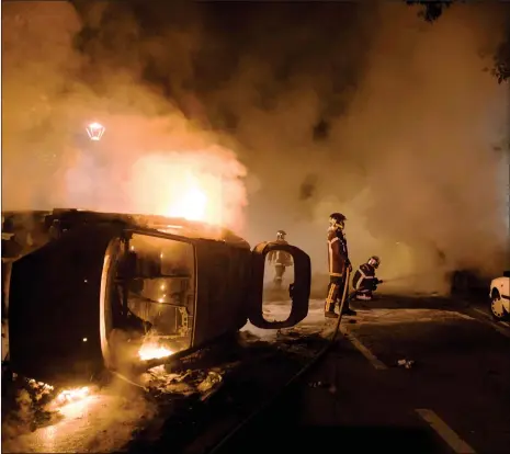  ?? Photo: AFP ?? Firefighte­rs work to put out a fire near a burning car in the Malakoff neighborho­od of Nantes early on Wednesday. Groups of young people clashed with police in the western French city of Nantes on the night of Tuesday after a man was shot dead by an...