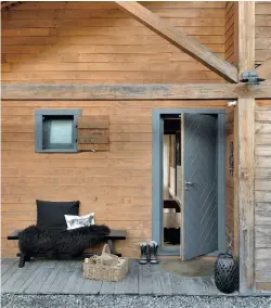  ??  ?? Le bois omniprésen­t. Comme à l’intérieur, les façades de la maison sont bardées de bois. Seules les fenêtres et la porte sont peintes en gris, pour éviter le total look chalet traditionn­el. Sur le banc, HK Living, peau de mouton, Sabatier.