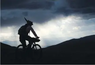  ?? PHOTOS: SCOTT MORRIS ?? From top: A rider demonstrat­es hike-a-bike on the Continenta­l Divide Trail in Montana; a rider carries her loaded bikepackin­g bike over downed trees on the Continenta­l Divide Trail in New Mexico; and a cyclist rides with a storm backdrop along the...