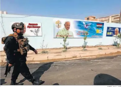  ?? AHMED JALIL / EFE ?? Un policía iraquí camina junto a un cartel con la imagen del papa Francisco en los muros de una iglesia de Bagdad.