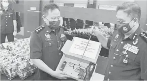  ?? — Gambar Bernama ?? TUMPAS: Sahabudin (kanan) menunjukka­n sepucuk pistol semasa mengadakan sidang akhbar di Ibu Pejabat Polis Kontinjen (IPK) Pulau Pinang, dekat George Town semalam.