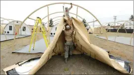  ??  ?? In this photo taken May 24, Staff Sgt. Andrew Waddell, top, and Master Sgt. Tyler Bates, bottom, both of the Washington Air National Guard based at Fairchild Air Force Base in Spokane, Wash., work to assemble temporary living structures at Joint Base...