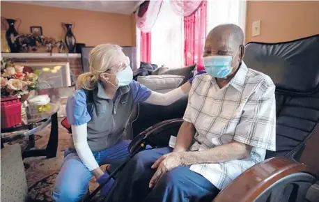  ?? STEVEN SENNE/AP ?? Geriatrici­an Megan Young offers support to Edouard Joseph after giving the 91-year-old a COVID-19 vaccinatio­n Feb. 11 at his home in Boston.