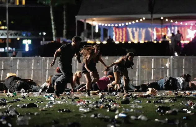  ?? David Becker/AFP ?? Jovens correm desesperad­os entre pessoas caídas na principal rua de Las Vegas, onde ocorria um festival de música, quando homem um começou a atirar