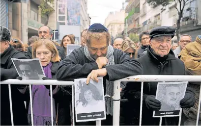  ??  ?? Calle Pasteur. Familiares y allegados a las víctimas del atentado portan ayer sus retratos frente a la AMIA.