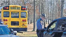  ?? [AP PHOTO] ?? A Kentucky State Police trooper checks with a motorist entering Marshall County High School on Wednesday near Benton, Ky. Two students died and another 18 people were injured in a shooting on Tuesday.