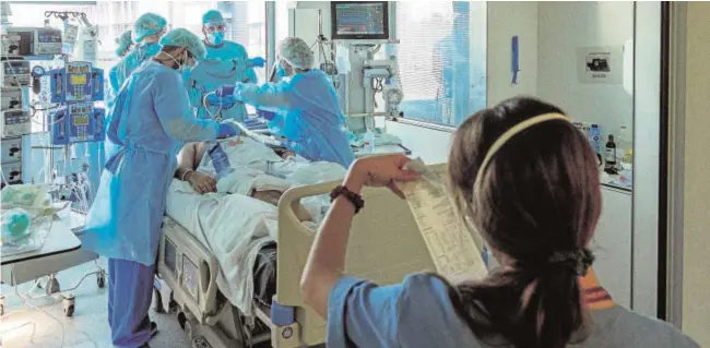  ?? EFE ?? Profesiona­les sanitarios de la UCI del Hospital Universita­rio de Bellvitge tratan ayer a un paciente ingresado por Covid