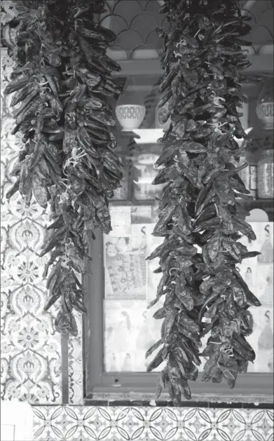  ?? JEFF KOEHLER ?? A strand of dried chiles hangs outside a spice shop in Nabeul, Tunisia. Soaked in water to soften, the chiles are ground with garlic, salt and spices to make the country’s ubiquitous condiment, harissa.