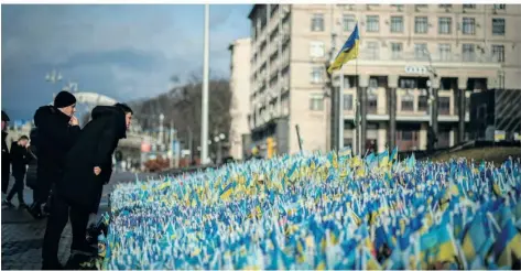  ?? FOTO: KAY NIETFELD/DPA ?? Passanten stehen vor ukrainisch­en Flaggen für getötete Soldaten am Maidan. Die Maidan-Revolution jährt sich zum zehnten Mal.