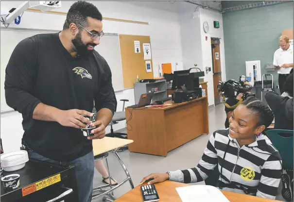  ?? (File Photo/AP/Steve Ruark) ?? John Urschel (left), a math scholar and former Baltimore Ravens lineman, hands out ice cream to Chelsy Valerio, 14, of Baltimore during a lesson at Dundalk High School during the launch of Texas Instrument­s’ STEM Behind Cool Careers series in Baltimore in July 2017.