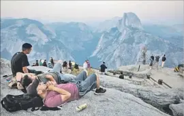  ?? Marcus Yam Los Angeles Times ?? VISITORS take in Half Dome at sunset in smoke-shrouded Yosemite Valley. The massive Detwiler fire is burning about 20 miles west of the national park.