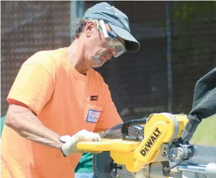  ?? JEFF VORVA/DAILY SOUTHTOWN PHOTOS ?? ABOVE: Lou Reimer, a 40-year member of St. Julie Billiart Parish in Tinley Park, saws lumber Friday to help make walls for a house that will be donated to a family in need in Elwood.