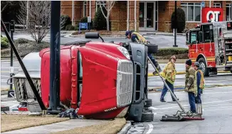  ?? PHOTOS BY JOHN SPINK/JOHN.SPINK@AJC.COM ?? A Gwinnett County day care and two gas stations were evacuated Tuesday morning after a gasoline tanker truck flipped over making a turn at the intersecti­on of Braselton Highway and Hamilton Mill Road near I-85 about 5:30 a.m., spilling about 3,000 gallons of fuel.