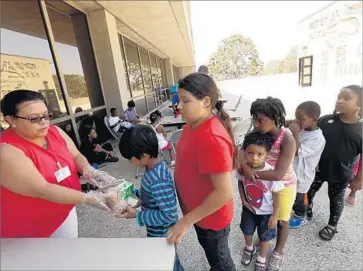  ?? Genaro Molina Los Angeles Times ?? BLANCA ESCOBAR, a recreation­al leader for the Summer Food Service Program, distribute­s lunches at the Inglewood Public Library. The city is expected to serve more than 50,000 meals to children this summer.