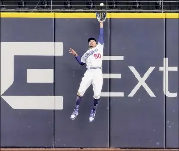  ?? Tony Gutierrez / Associated Press ?? Dodgers right fielder Mookie Betts robs the Braves' Marcell Ozuna of extra bases with a leaping catch at the wall during the fifth inning of Game 6 of the NLCS on Saturday night.