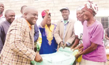  ?? - Picture by Munyaradzi Chamalimba (See story on Page 7) ?? Minister of State for Mashonalan­d Central Provincial Affairs Advocate Martin Dinha hands over fertiliser to Mai Keti Kakora during the rollout of the 2017-18 Presidenti­al inputs Support Scheme at Bare Shopping Centre in Chiweshe yesterday.