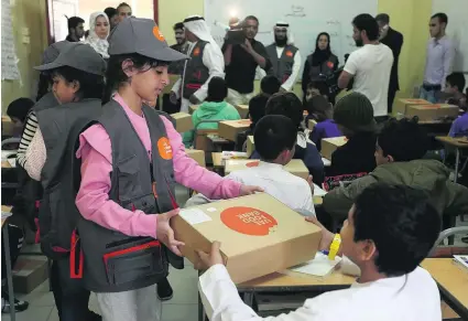  ?? Satish Kumar / The National ?? Sheikha Mahra bint Ammar Al Nuaimi, the 10-year-old daughter of Ajman Crown Prince Sheikh Ammar bin Humaid, distribute­s food boxes at Manar Al Eman Charity School yesterday as part of a volunteer programme of the UAE Food Bank initiative.