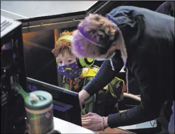  ??  ?? Garret Purvines, of the HyperX Esports Arena staff, assists Liam Lose, 7, of Las Vegas, in setting up his computer for a “Friday Night Frags” Fortnite tourney.