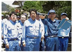  ?? — AFP ?? Devastatin­g scene: Abe (centre) inspecting a flood-hit area in the city of Seiyo, Ehime prefecture.