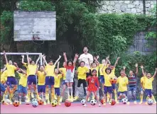  ?? PHOTOS PROVIDED TO CHINA DAILY ?? Above: Li Huixi poses with members of the children’s soccer team he and Xu Tao founded at Hongjiang.