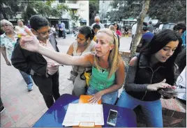  ?? Fernando Llano The Associated Press ?? People fill out forms Tuesday in Caracas to join volunteers who will help move humanitari­an aid into Venezuela. The opposition expects to mobilize on Saturday.