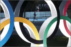  ?? AP FILE PHOTO/JAE C. HONG ?? In this March 30 file photo, a man jogs past the Olympic rings in Tokyo.