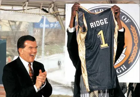  ?? Bob Donaldson ?? A delighted Gov. Tom Ridge gets a Pitt basketball jersey from men’s team captain Vonteego Cummings in 1998. Mr. Ridge is in critical condidtion after a heart procedure.