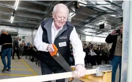  ??  ?? President of the Victorian Men’s Shed Associatio­n Lindsay Oates saws a piece of timber – not a ribbon – to officially open the new Warragul Woodworker­s Club headquarte­rs at Lillico.