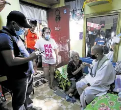  ?? — PHOTOS BY LYN RILLON ?? VISITING SHEPHERD Lourdes Huertas (center) holds the hand of her shepherd, Fr. Robert Reyes of the San Isidro Labrador Parish, during his visit to the home she shares with family members. Bro. Arvin Zarsata (left) is present to assist in the rituals.