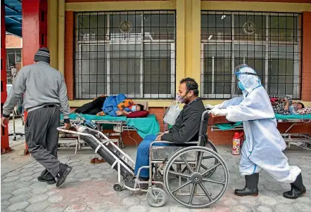  ?? AP ?? A Covid-19 patient arrives in a wheelchair as others rest outside the emergency ward of a hospital in Kathmandu yesterday. Doctors in Nepal, across the border from a devastatin­g coronaviru­s surge in India, have warned of a major crisis as daily cases hit record numbers and hospitals run out of beds and oxygen.