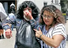  ??  ?? Mujeres se ayudan mutuamente a desalojar el edificio de la Lotería Nacional conocido como El Moro que resultó con daños.
