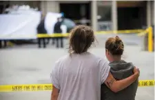  ??  ?? Two students embrace while watching the removal of a body of one of the deceased. Photo: AP