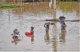  ?? — PTI ?? Flood-affected residents carry their belongings as they relocate from a low-lying area on the bank of the Ganga river to a safer place in Patna on Friday.