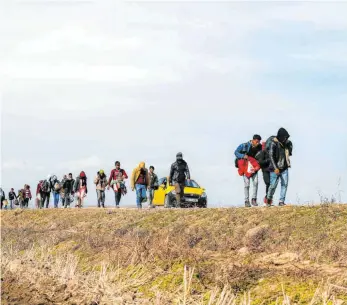  ?? FOTO: EMRAH GUREL/DPA ?? Migranten gehen an der türkischen Seite der Grenze zu Griechenla­nd eine Straße entlang.