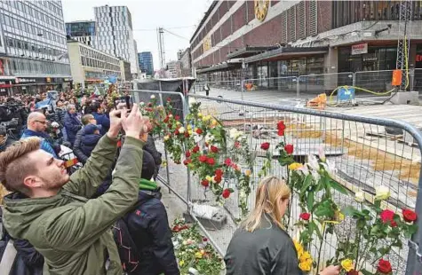  ?? Reuters ?? People gather at the crime scene, near Ahlens department store yesterday, the day after a hijacked truck ploughed into pedestrian­s on Drottningg­atan and crashed into Ahlens department store, in central Stockholm, Sweden.