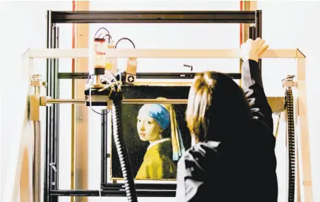  ?? Bart Maat / AFP / Getty Images ?? Johannes Vermeer’s “Girl With a Pearl Earring” painting is inside an XRF macro-scanner during research at Mauritshui­s.