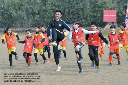  ?? PHOTO AFP ?? Des jeunes pakistanai­s s’entraînent avec un entraîneur local sur le terrain de la nouvelle académie de l’Atletico Madrid à Lahore, au Pakistan.