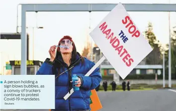  ?? Reuters ?? A person holding a sign blows bubbles, as a convoy of truckers continue to protest Covid-19 mandates.