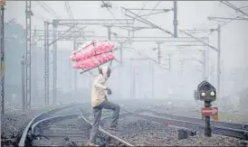  ?? PTI PHOTO ?? A cotton candy vendor crosses a railway track on a cold and foggy winter morning, in Prayagraj on Wednesday.